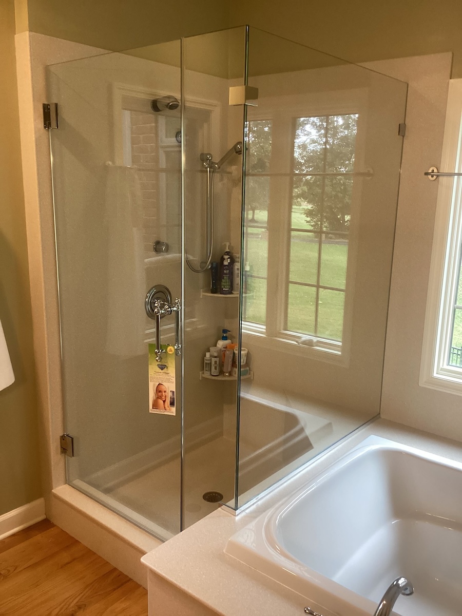frameless glass corner shower enclosure beside soaking tub